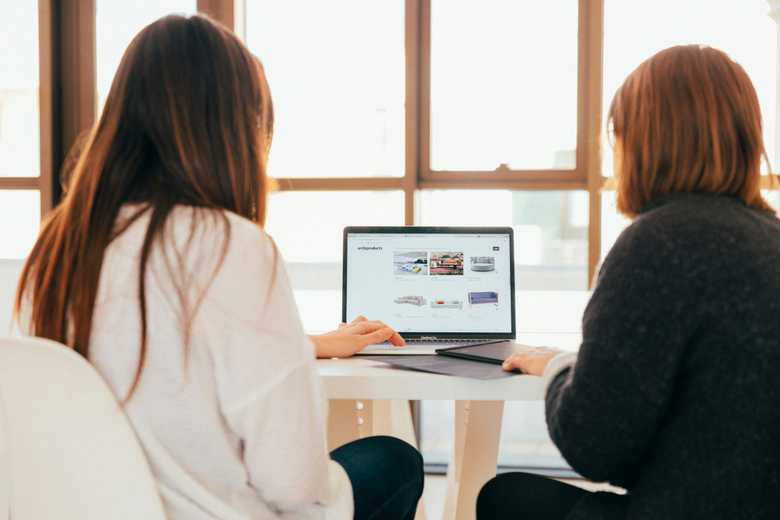 Two women talking while looking at the laptop